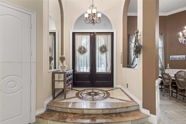 tiled foyer entrance with an inviting chandelier, ornamental molding, and french doors