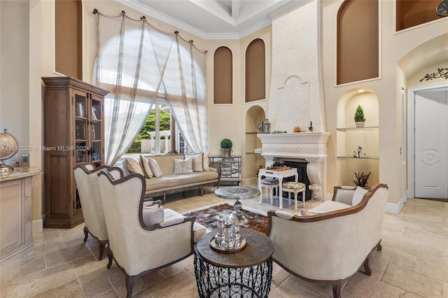 tiled living room with a towering ceiling, built in features, a fireplace, and crown molding