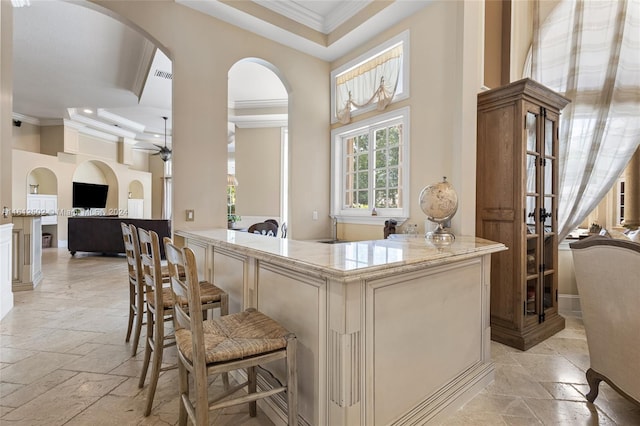 bar with a raised ceiling, light stone counters, cream cabinets, and light tile floors