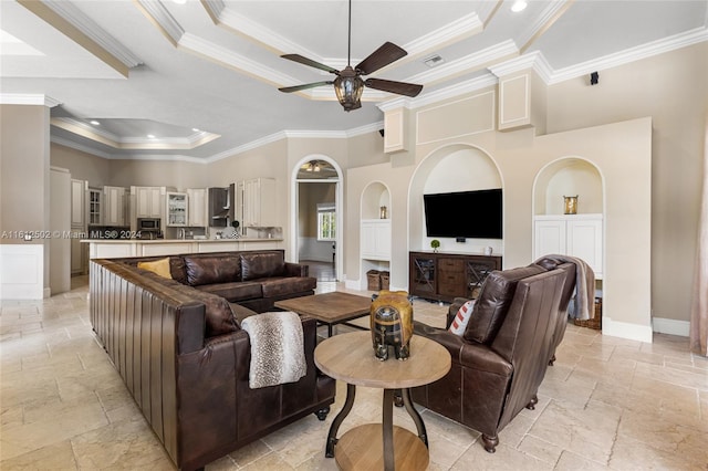 tiled living room with crown molding, ceiling fan, and a raised ceiling