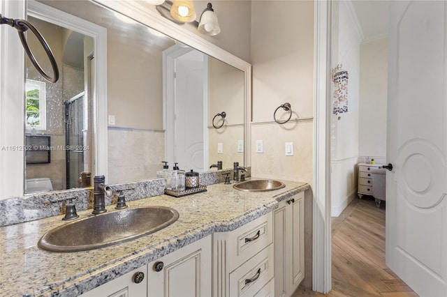 bathroom featuring hardwood / wood-style floors, oversized vanity, dual sinks, and crown molding