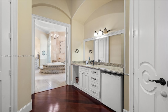 bathroom featuring hardwood / wood-style floors, tiled bath, and large vanity