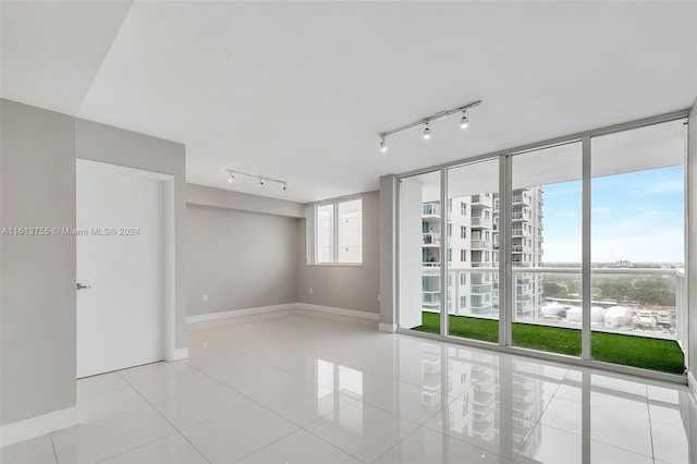 spare room with a wall of windows and light tile patterned floors