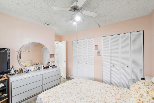 11091 NW 7th St Unit 202, Miami, FL 33172 - bedroom with light wood-style floors, a textured ceiling, a ceiling fan, visible vents, and multiple closets