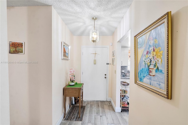 11091 NW 7th St Unit 202, Miami, FL 33172 - interior space featuring baseboards, light wood-style flooring, a textured ceiling, and an inviting chandelier