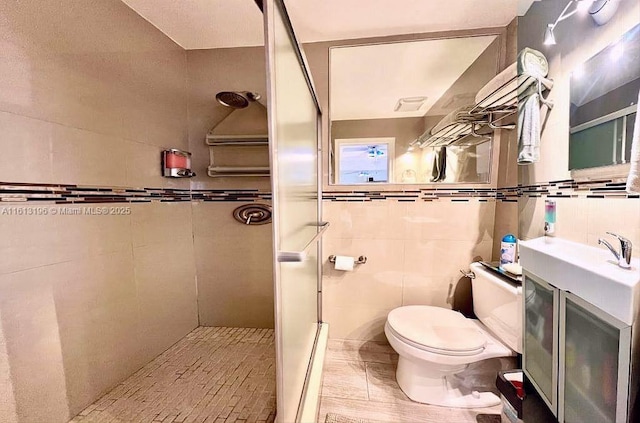 bathroom with tile walls, vanity, toilet, and tiled shower