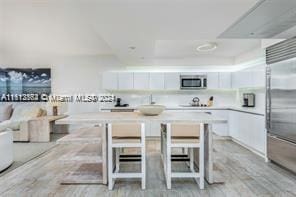 kitchen featuring stainless steel appliances, white cabinets, and a kitchen breakfast bar