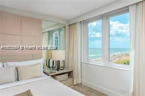 bedroom with a water view, a view of the beach, and multiple windows