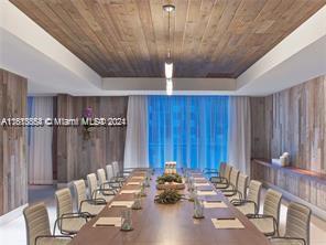 unfurnished dining area featuring hardwood / wood-style flooring, wooden walls, wooden ceiling, and a raised ceiling