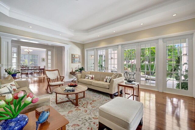 dining area with crown molding, built in features, a notable chandelier, dark hardwood / wood-style flooring, and a raised ceiling