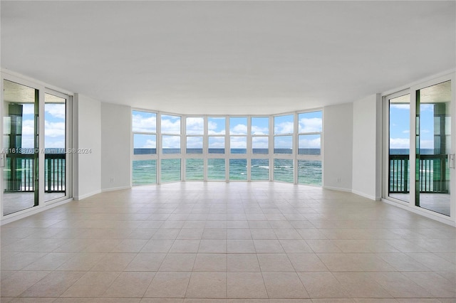 tiled empty room with plenty of natural light and a water view