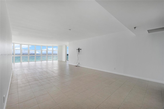 tiled spare room with expansive windows and a water view