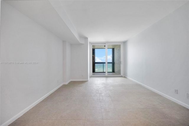 unfurnished room with floor to ceiling windows and light tile floors