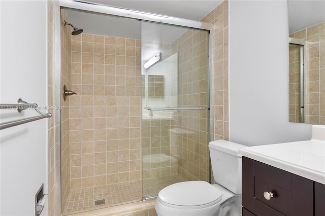 bathroom featuring a shower with door, toilet, and vanity