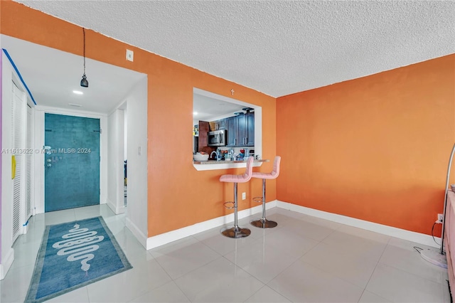 hallway with light tile patterned flooring and a textured ceiling