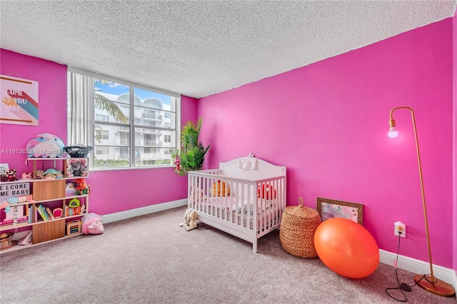 bedroom with carpet, a textured ceiling, and a nursery area