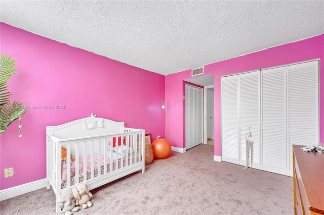 carpeted bedroom featuring a crib, a textured ceiling, and a closet