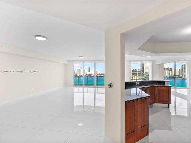 kitchen with light tile patterned flooring, a water view, kitchen peninsula, and sink