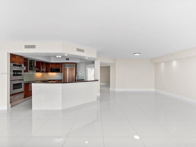 kitchen featuring wall chimney exhaust hood, light tile patterned floors, double oven, tasteful backsplash, and paneled fridge