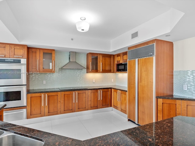 kitchen with black appliances, wall chimney range hood, and backsplash