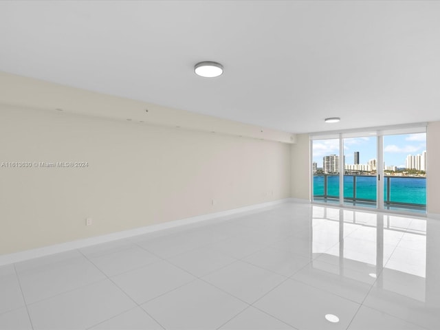 empty room with floor to ceiling windows and light tile patterned floors