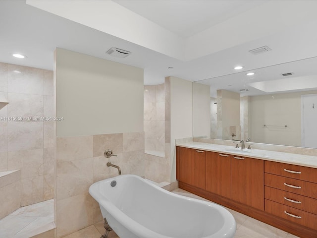 bathroom with tile patterned flooring, vanity, a bathing tub, and tile walls