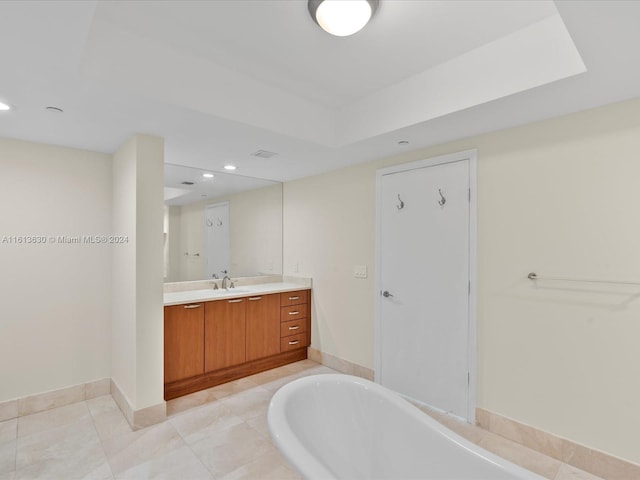 bathroom with vanity, a raised ceiling, and tiled bath