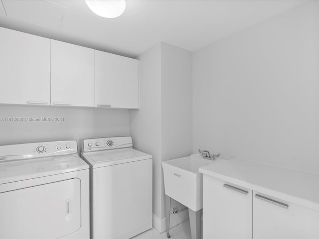 clothes washing area featuring cabinets, washing machine and dryer, and sink