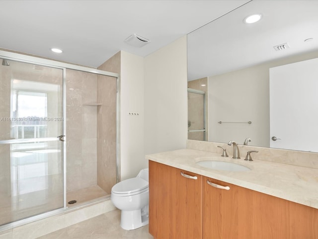 bathroom with tile patterned floors, vanity, an enclosed shower, and toilet