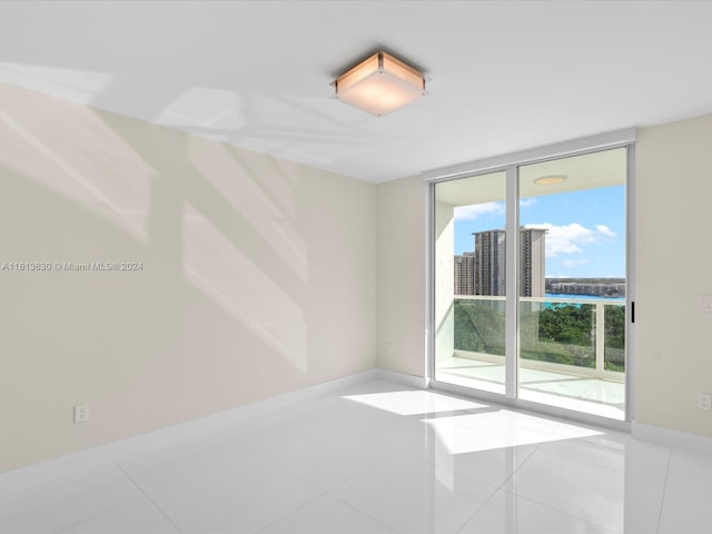 unfurnished room with light tile patterned flooring and a wall of windows