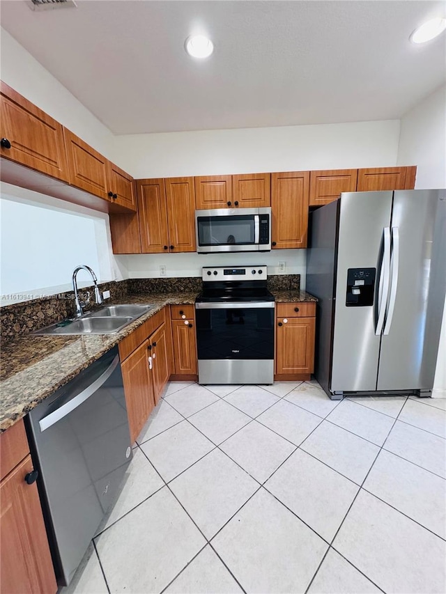 kitchen featuring light tile patterned flooring, sink, appliances with stainless steel finishes, and dark stone counters