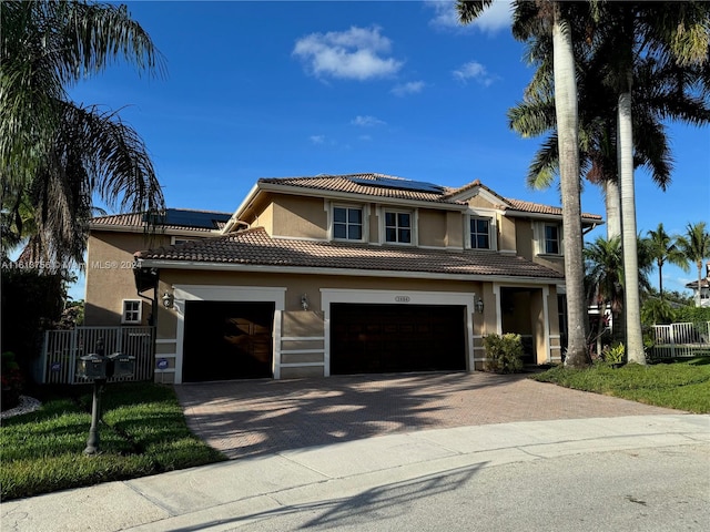 mediterranean / spanish-style home featuring solar panels, a garage, and a front yard