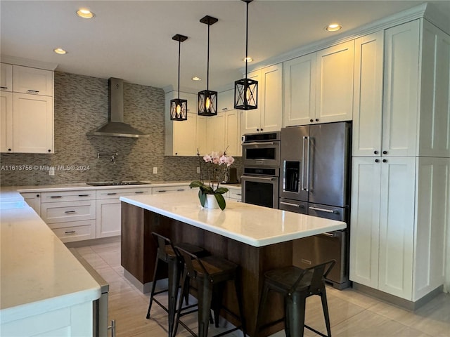 kitchen with wall chimney exhaust hood, tasteful backsplash, a kitchen island, and stainless steel appliances