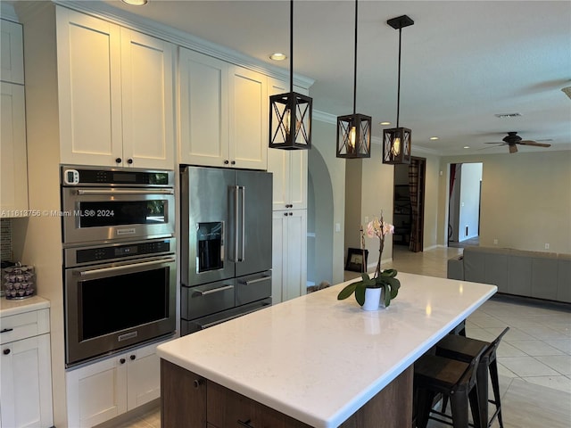 kitchen featuring white cabinets, a center island, ceiling fan, stainless steel appliances, and pendant lighting