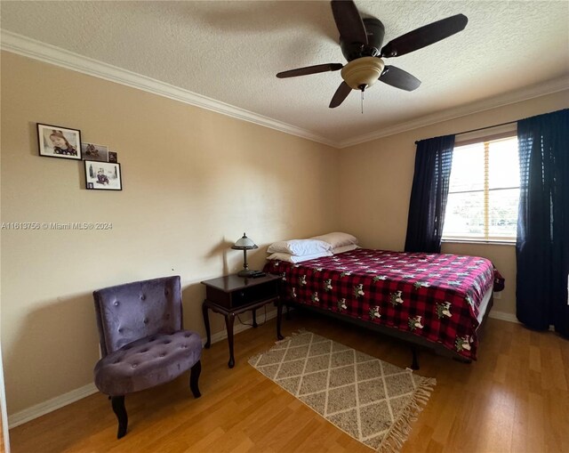 bedroom featuring wood-type flooring, a textured ceiling, ornamental molding, and ceiling fan