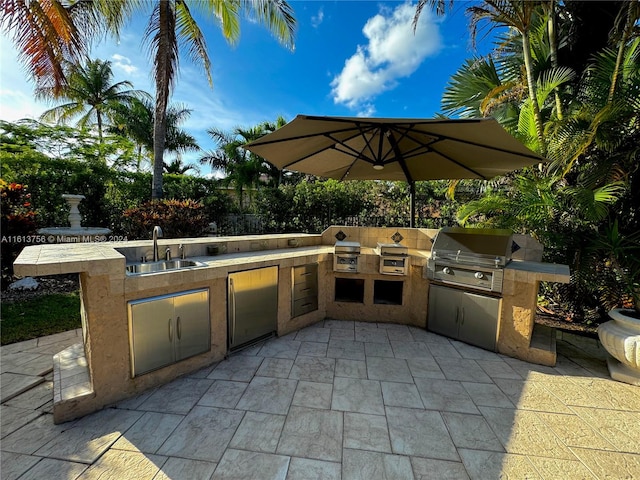 view of patio with sink, an outdoor kitchen, and a grill