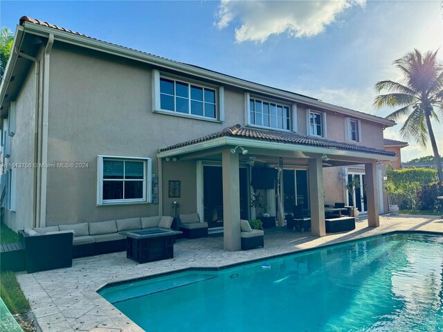 back of property with an outdoor living space with a fire pit, ceiling fan, and a patio area