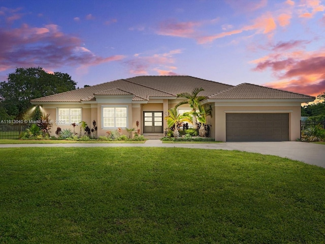 mediterranean / spanish-style house featuring a garage and a lawn