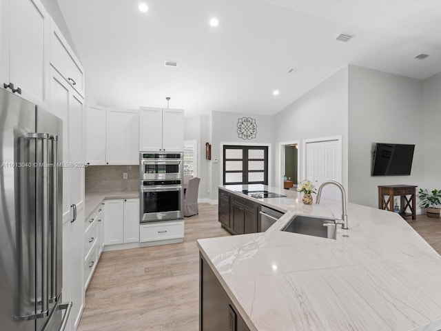 kitchen featuring light stone counters, sink, white cabinets, and stainless steel appliances