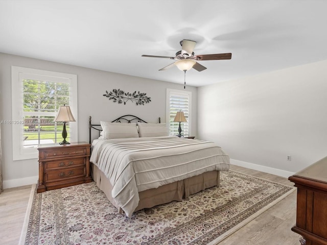 bedroom with ceiling fan, multiple windows, and light wood-type flooring