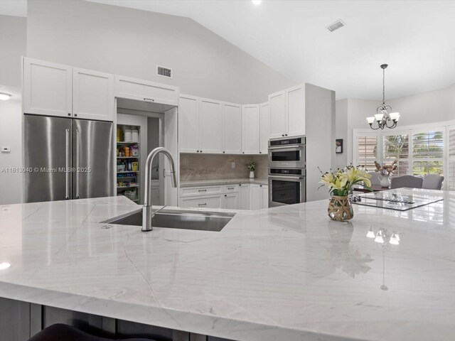 kitchen with light stone countertops, sink, stainless steel appliances, and tasteful backsplash