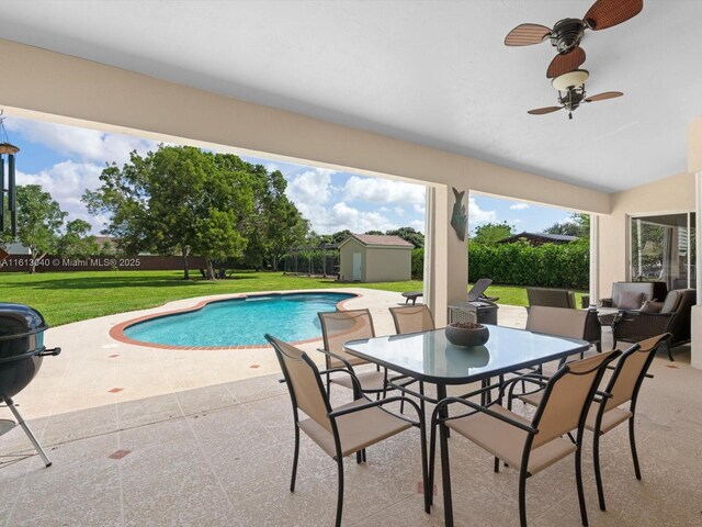 view of pool featuring a patio, a lawn, grilling area, and a shed