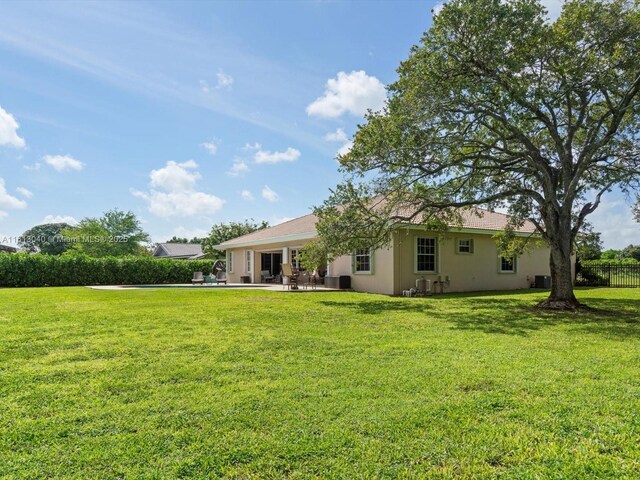 back of property with a patio area, central air condition unit, and a lawn