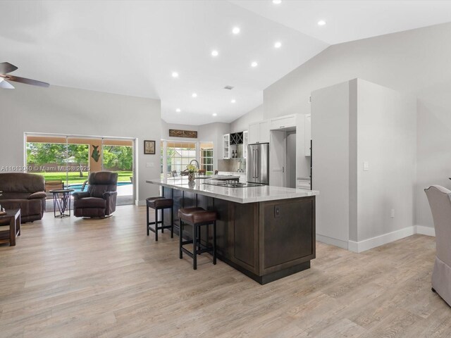 kitchen featuring a spacious island, white cabinetry, light wood-type flooring, a breakfast bar, and high end refrigerator