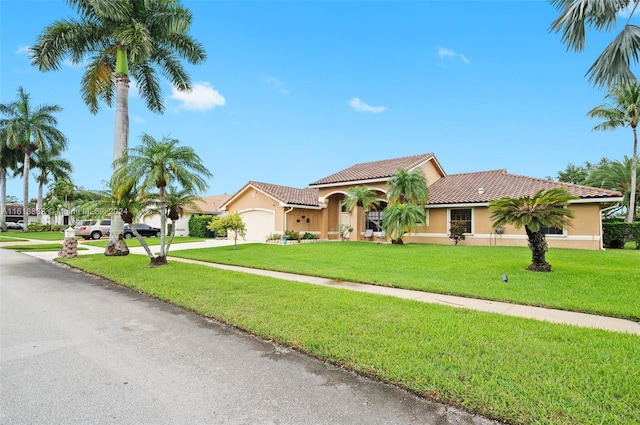 mediterranean / spanish-style house featuring a tile roof, concrete driveway, a front yard, stucco siding, and a garage