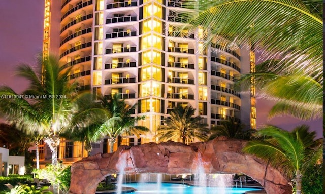 outdoor building at dusk featuring a community pool and pool water feature