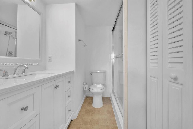 bathroom featuring vanity, a shower with shower door, and toilet