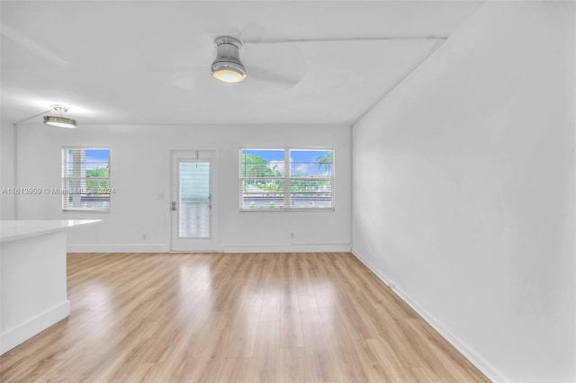 empty room with light wood-type flooring, ceiling fan, and a healthy amount of sunlight