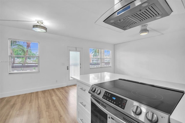 kitchen with stainless steel electric stove, white cabinetry, and light wood-type flooring