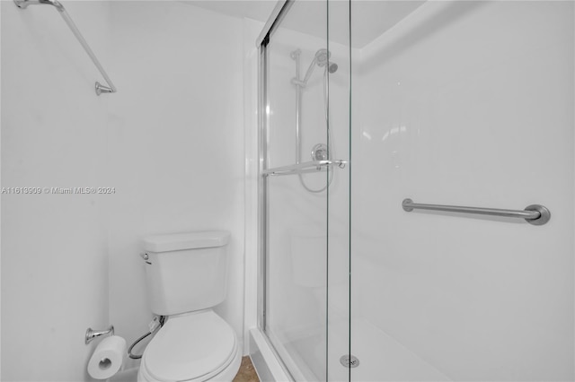 bathroom with toilet and a shower with door